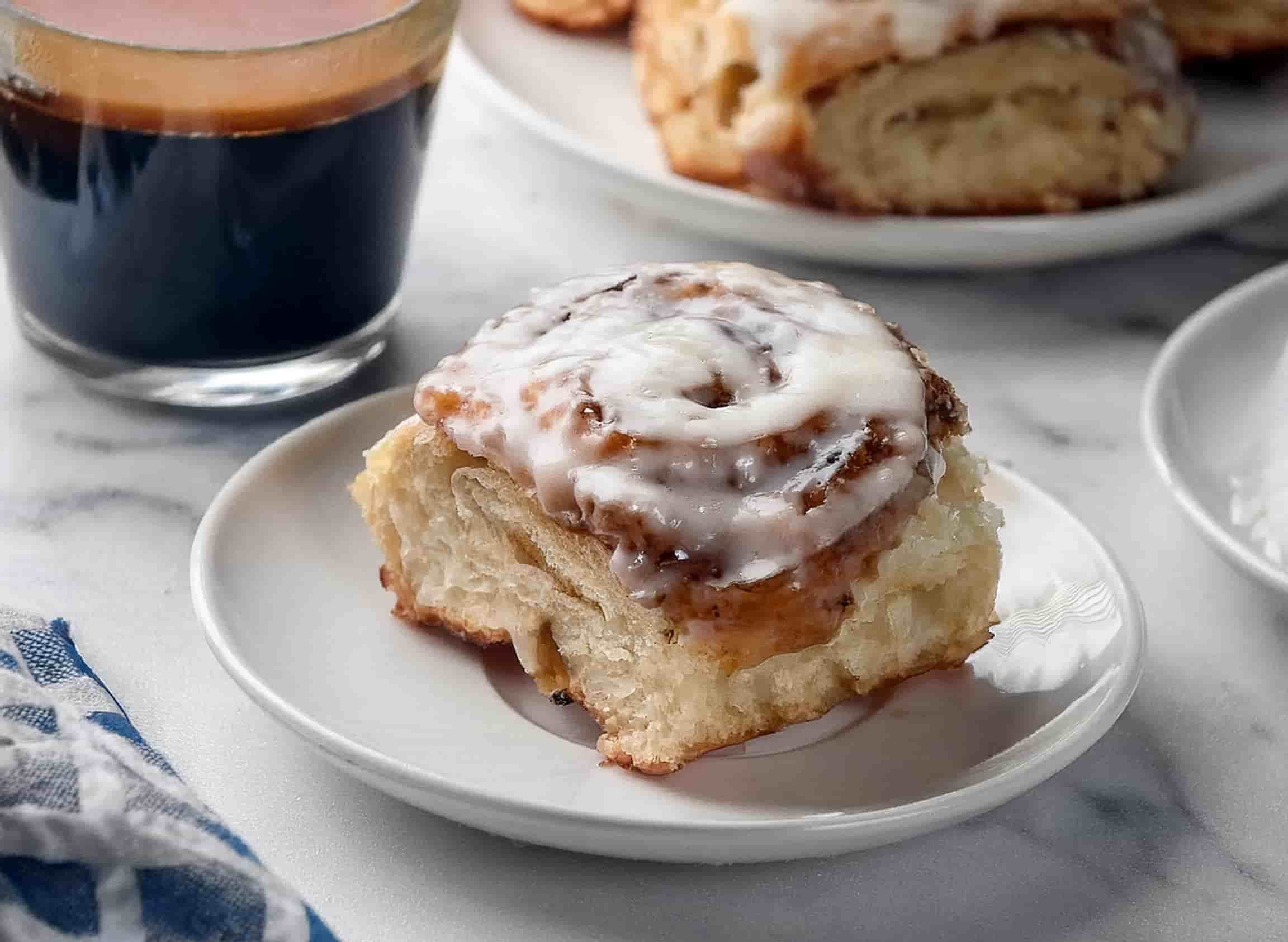 Freshly baked Rhodes cinnamon rolls in a pan, topped with creamy frosting and a glossy cinnamon-sugar glaze.