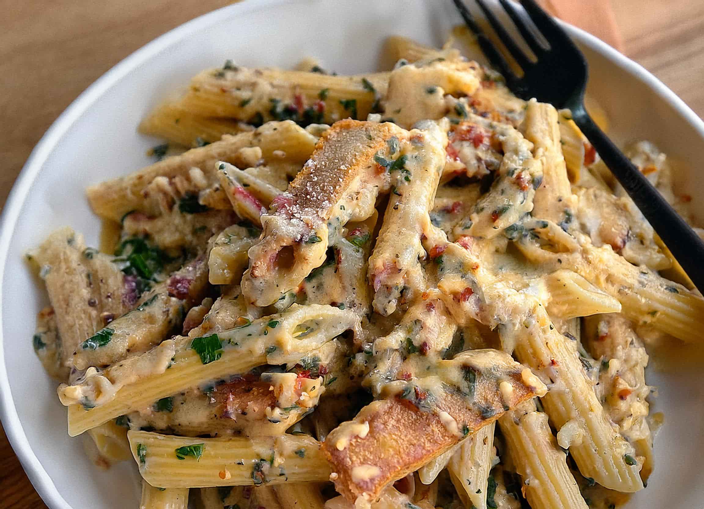 Creamy Garlic Parmesan Chicken Pasta served in a skillet, topped with fresh parsley and surrounded by ingredients like grated Parmesan and garlic cloves