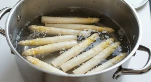 White asparagus spears simmering in a pot of boiling water for a traditional asparagus German recipe.