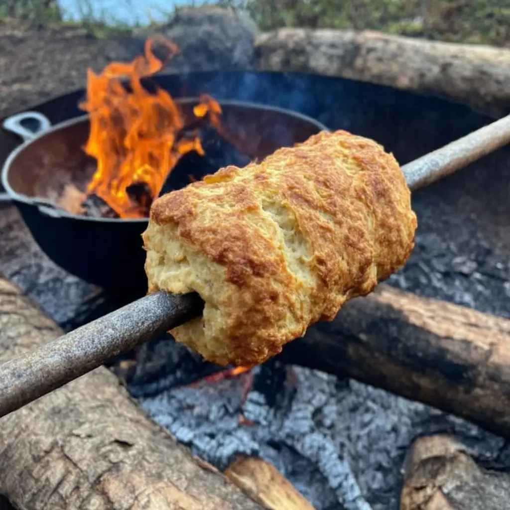 Golden bannock on a stick held over fire