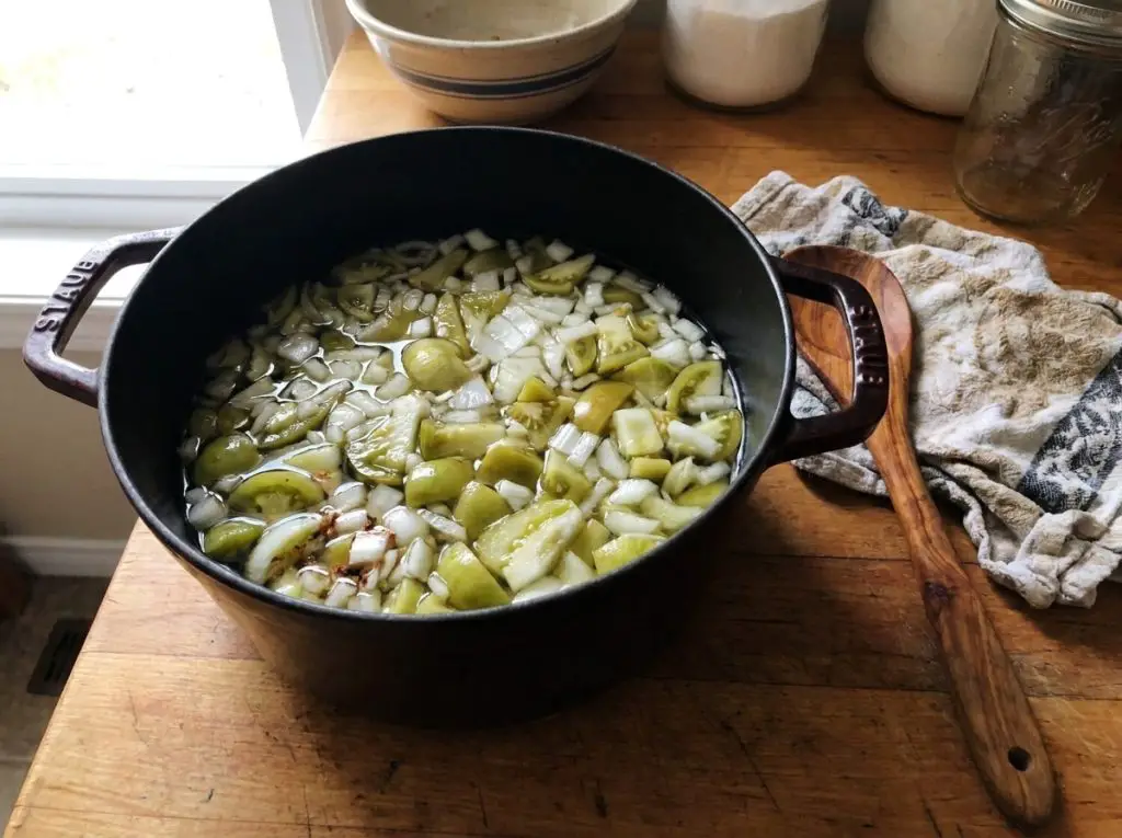 Green tomatoes and onions in a pot with vinegar to cook into chow chow.
